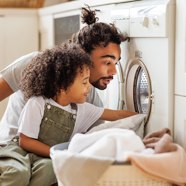 A father and son unloading clothes from a dryer